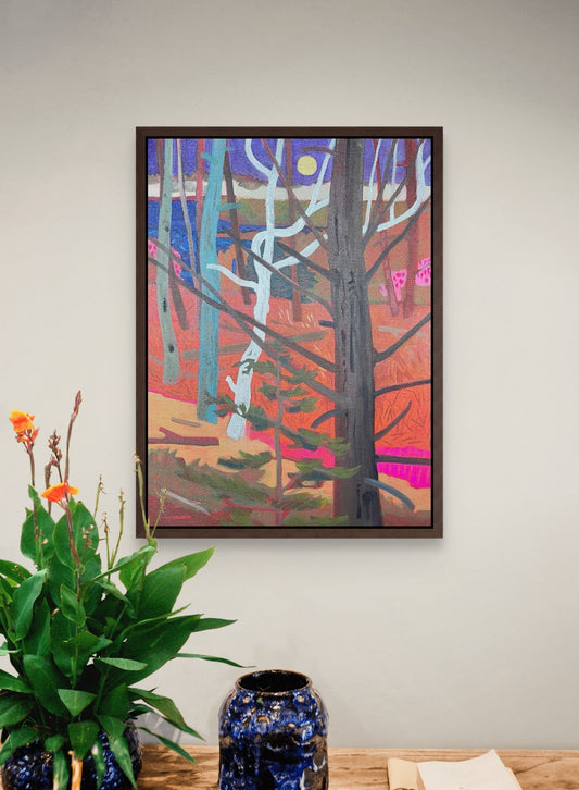 Framed abstract artwork of a forest scene on a wall above a wooden table with decorative items.