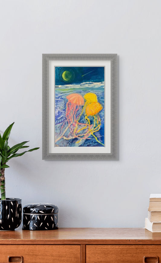 Framed artwork of jellyfish on a wall above a wooden cabinet.