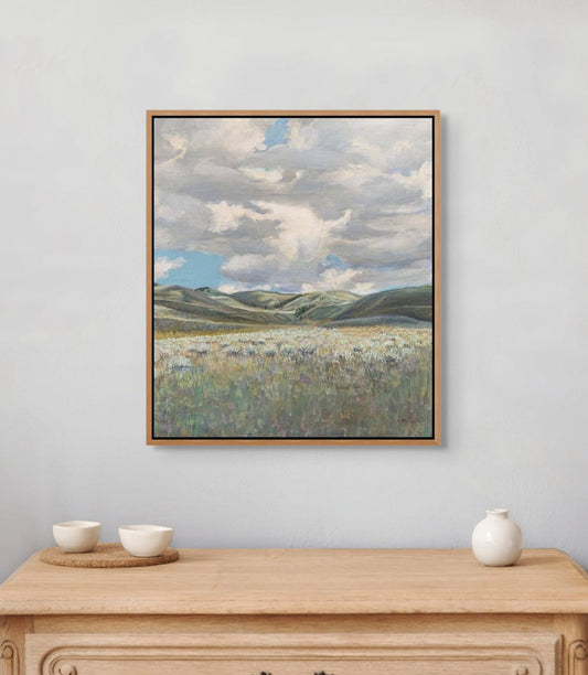 Framed landscape painting above a wooden dresser with decorative items.